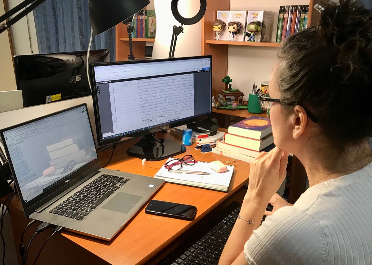 Tati Marin em seu ambiente de pesquisa, analisando um registro histórico